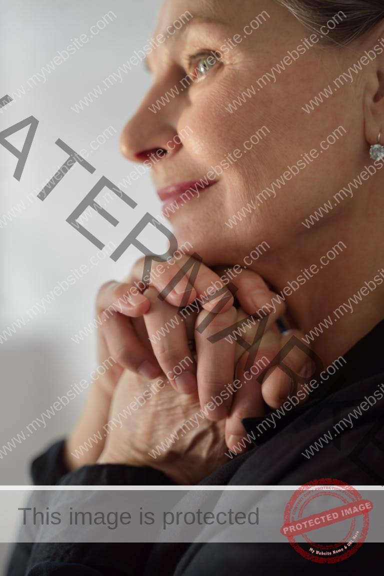 Elegant portrait of a senior woman with hands clasped, exuding contemplation and serenity.