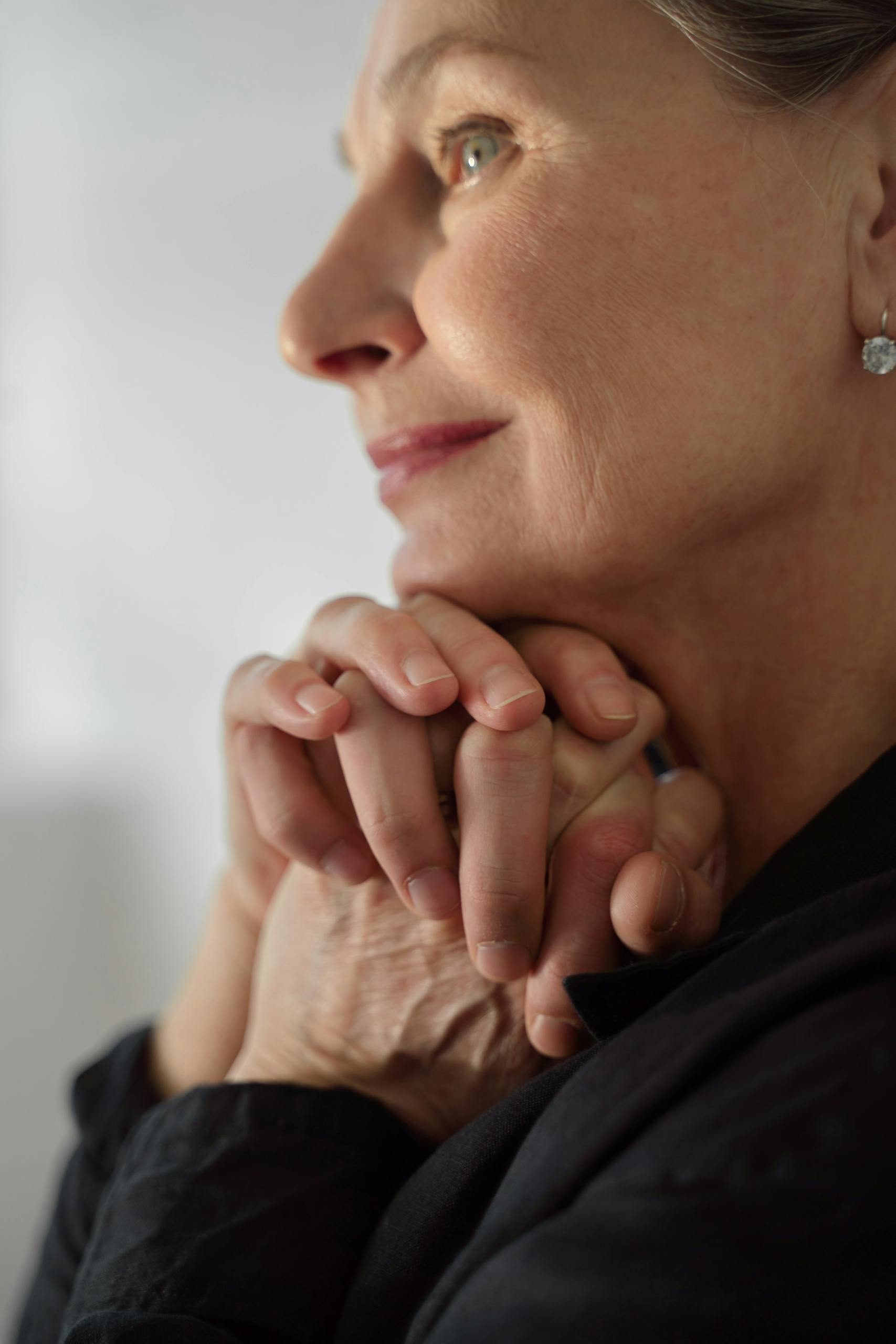 Elegant portrait of a senior woman with hands clasped, exuding contemplation and serenity.
